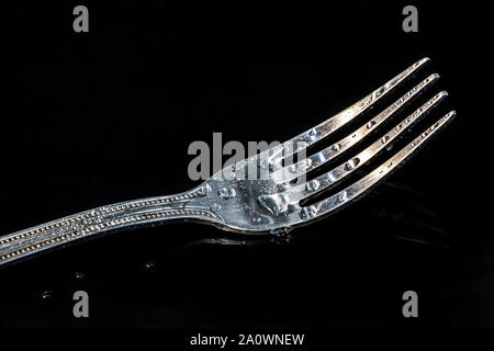 Single fork at the black table with water droplets on it. Stock Photo