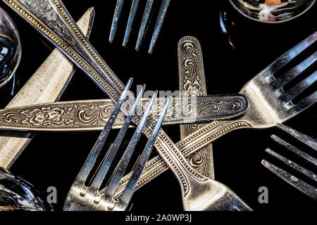 Abstract mix of forks, spoons and knives on a black background. Stock Photo
