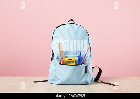 school blue backpack with stationery in pocket isolated on pink Stock Photo