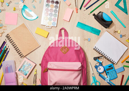 top view of various school supplies with pink backpack on wooden desk Stock Photo
