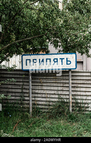 PRIPYAT, UKRAINE - AUGUST 15, 2019: sign with pripyat lettering near fence and trees Stock Photo