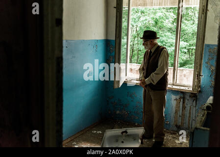 sad senior man standing in damaged room Stock Photo