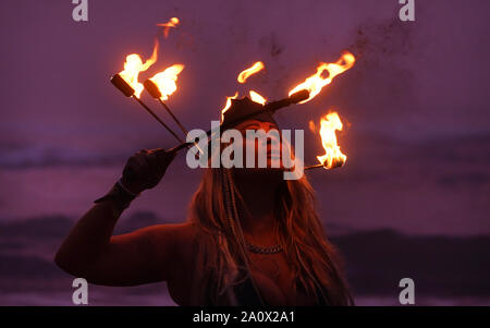 Fire performer Penella Bee performs before people take part in the North East Skinny Dip at Druridge Bay in Nothumberland, an annual event that marks the Autumn Equinox and raises money for MIND - the Mental Health Charity. Stock Photo