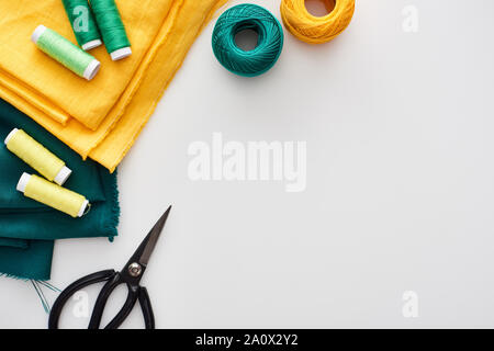 top view of fabric, knitting yarn balls, scissors and threads on white background Stock Photo