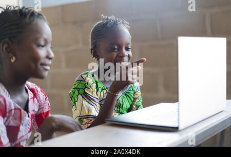 Two Funny Girls Smiling and Laughing at Computer Laptop Screen Stock Photo