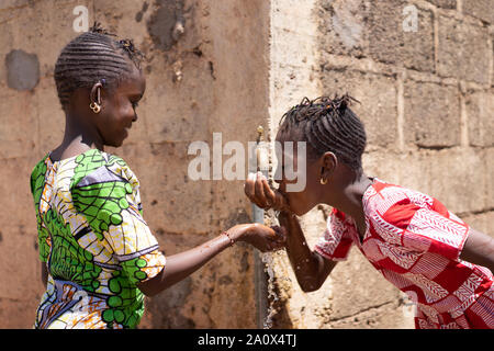 Adorable Little African Girls Drinking Fresh Water from Tap Stock Photo
