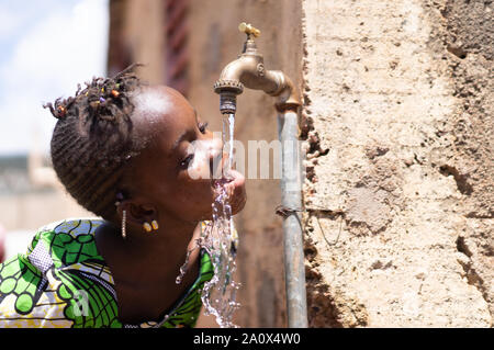 Joyful Black Child Drinks Fresh Water from a Tap Stock Photo