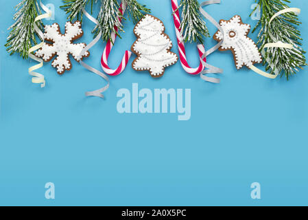 Frame with fir branches, cookies and Christmas decorations on a blue background. Top view. Stock Photo