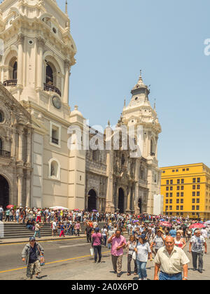 Lima, Peru - March 29, 2018: People with colorful umbrellas on a hot day on the street of Lima next to Parroquia del Sagrario. Easter time. Maundy Thu Stock Photo