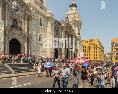 Lima, Peru - March 29, 2018: People with colorful umbrellas on a hot day on the street of Lima next to Parroquia del Sagrario. Easter time. Maundy Thu Stock Photo