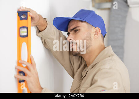 young tradesman using a spirit level on wall Stock Photo