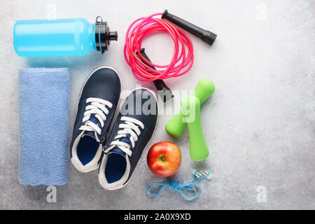 Set of various fitness equipment - sneakers, dumbbells, water bottle, skipping rope and towel. Outfit for gym or home. Copy space. Stock Photo