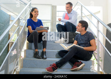 teacher and two students sat on stairs Stock Photo