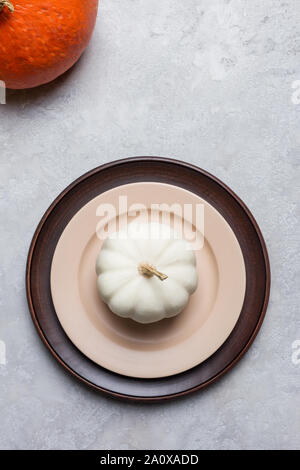 Seasonal empty plate with pumpkin on gray concrete background with orange squash in corner. Concept of thanksgiving table set Stock Photo