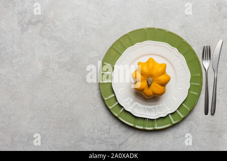 Table set with whole decor yellow pumpkin on empty plate. Horizontal image for text. Concept of harvest and Thanksgiving table set. Minimal top view, Stock Photo