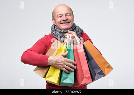 Senior hispanic man holding colored shopping bagsafter shopping in the mall. Stock Photo