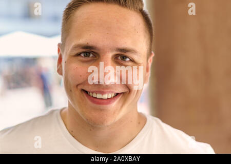 Close-up front portrait of a happy young man smiling while looking at camera with confidence and positive thinking indoors Stock Photo