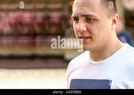 Thoughtful young man in casual T-shirt walking in an urban street with a pensive  look Stock Photo