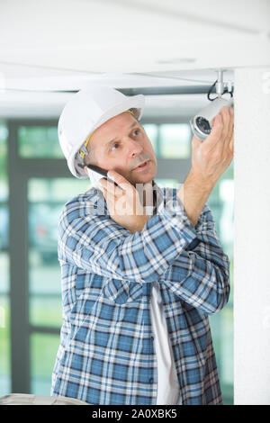 contractor by security camera talking on telephone Stock Photo