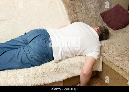 Man in white shirt lies on the sofa. Man sleeping on the couch Stock Photo