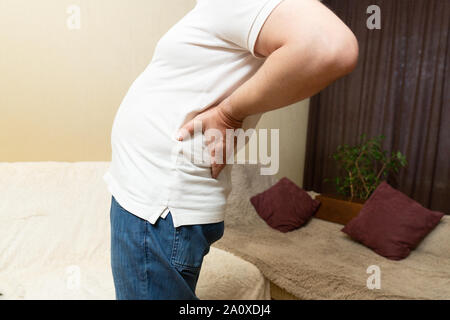 Lower back pain. Man in white shirt holding his back in pain Stock Photo