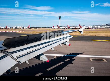 View from plane window over wing landing on airport runway with Virgin Atlantic aeroplanes, London, England, UK Stock Photo