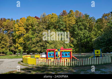 Autumn view of a children's playground in a natural forest with a wooden railway and an outdoor slide, South Park, Sofia, Bulgaria Stock Photo