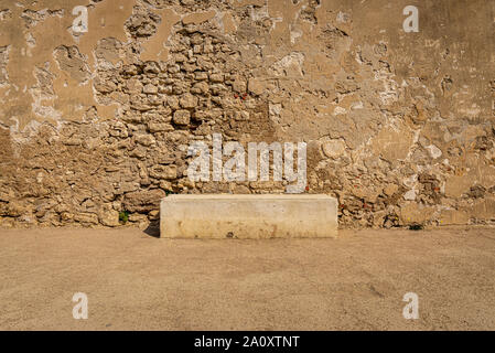 Concrete bench against weathered stone and crepis wall. Taken on a summer afternoon, Bonifacio, France Stock Photo