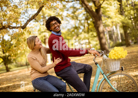 Multiracial young couple riding on a bicycle at the autumn park Stock Photo