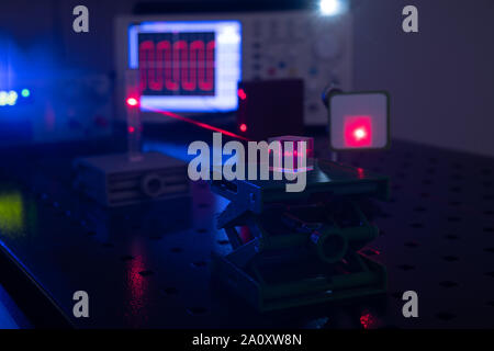 Experiment in optic lab with laser device. Red laser on optical table in physics laboratory Stock Photo