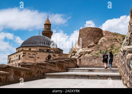 Dogubayazıt: Kurdish girls visiting Eski Bayezid Cami mosque near Ishak Pasha Palace with the castle of Old Beyazit on the road up to the mountains Stock Photo