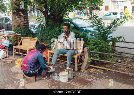 BAHIR DAR, ETHIOPIA, APRIL 21th. 2019, Traditional shoe cleaner on the street of Bahir Dar during easter holiday. April 21th. 2019, Bahir Dar, Ethiopi Stock Photo