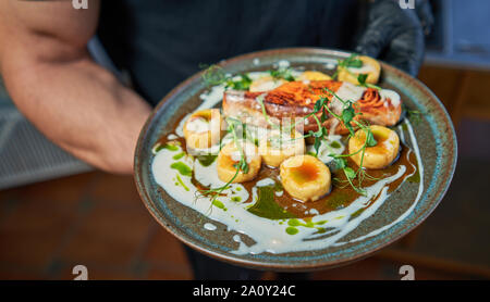 man holds a plate of fried salmon Stock Photo