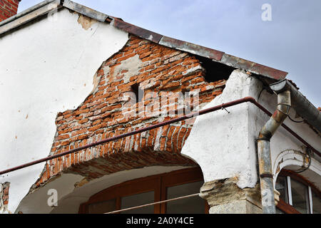 damaged plaster layer on old house; effects of rain water leakage from the roof, creating dampness inside the wall Stock Photo