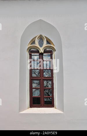 window on exteriorfacade of old gothic church with white painted walls Stock Photo