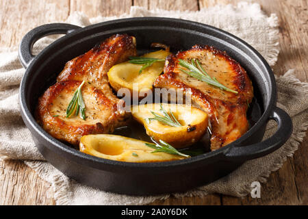 Hot spicy baked pork chops with pears and rosemary in honey-garlic sauce served in a pan close-up on the table. horizontal Stock Photo