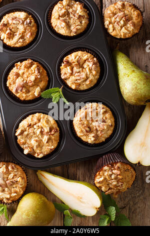 pear muffin with cinnamon and walnuts in a baking dish close-up on the table. Vertical top view from above Stock Photo