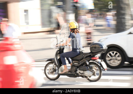Belgrade, Serbia - September 17, 2019 : One woman riding a vespa scooter in the city street traffic panning shot Stock Photo