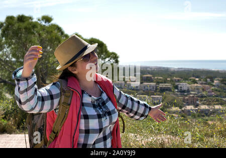 Attractive girl tourist joyfully dancing on the mountain against the backdrop of nature, positive emotions Stock Photo