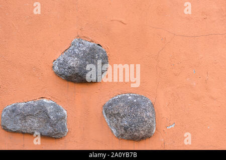 Three gray stones on an orange background. Stock Photo