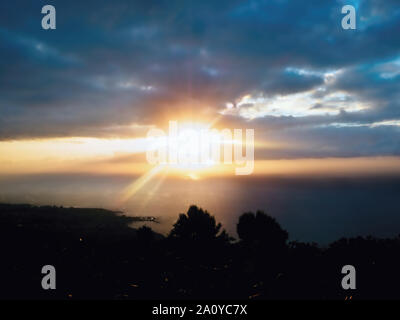 Sunset over the Atlantic Ocean in cloudy sky with silhouette of the north coast of the Canary Island Tenerife. Stock Photo