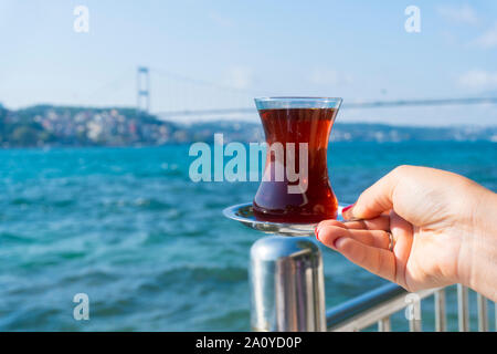 A hand holding a tea at istanbul bosphorus view Stock Photo