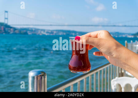 A hand holding a tea at istanbul bosphorus view Stock Photo