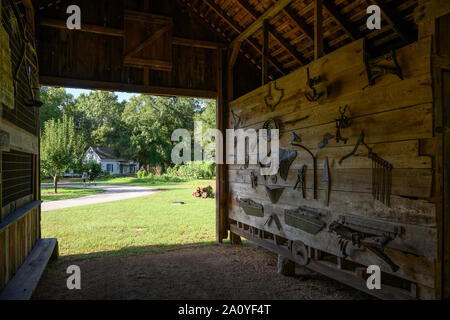 Farm tools hanging on the wall of an old Blacksmith shop preserved at Kleb Woods Nature Park. Houston, Texas, USA. Stock Photo