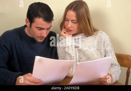 young couple sitting at table reading documents Stock Photo