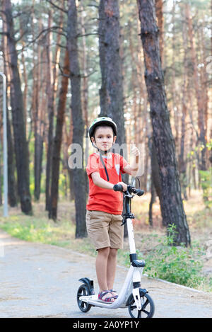 A boy rides a scooter in the forest. Stock Photo