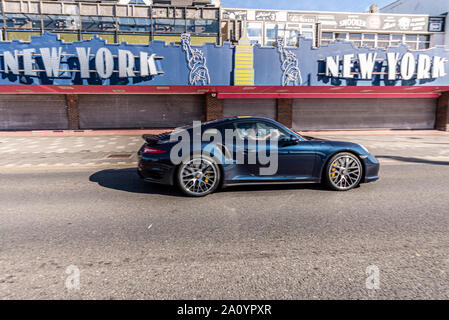 Porsche car driving past New York amusement arcade on Marine Parade, Southend on Sea, Essex, UK. Closed. Motion blur. Moving Stock Photo