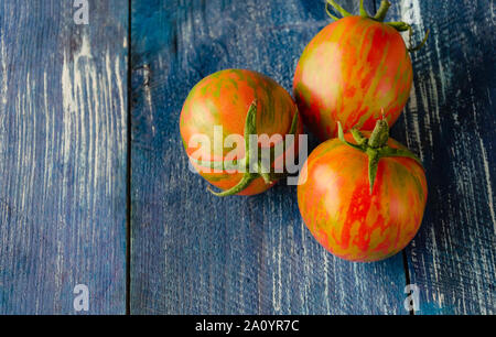 red tomatoes with a yellow pattern, natural organic tomatoes on a wooden table, closeup Stock Photo
