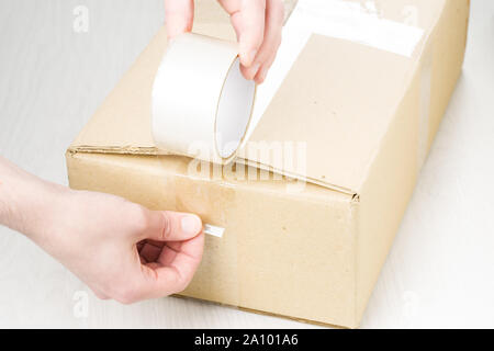 Hands with roll adhesive tape on a cardbox Stock Photo