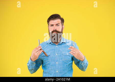 Designing haircut. Fresh hairstyle. Barbershop concept. Barbershop salon. Personal stylist barber. Bearded man hold razor and scissors. Classy and fabulous. Retro barbershop. Hipster with tools. Stock Photo